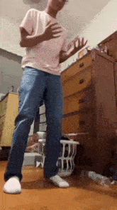 a man in a pink shirt and jeans is dancing in a room