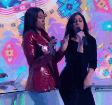 two women are standing next to each other singing into microphones .