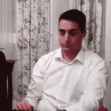 a man in a white shirt is sitting at a table