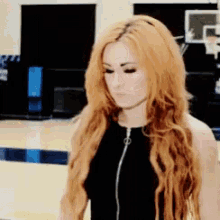 a woman with long red hair is wearing a black tank top with a zipper on the front .