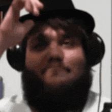 a man with a beard is wearing headphones and a top hat .
