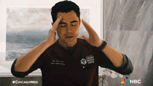 a man wearing a chicago medical center uniform holds his head