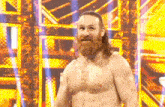 a shirtless wrestler with a beard is standing in front of a yellow wall .