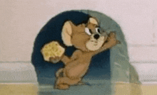jerry from tom and jerry is holding a piece of cheese in his paws .