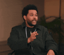 a man with a beard is wearing headphones and pointing his finger