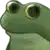 a green frog with big eyes is sitting on a white surface .