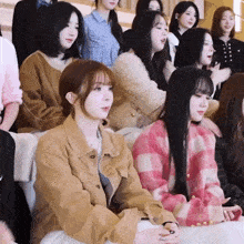 a group of women are sitting in a row and one of them is wearing a pink plaid sweater