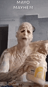 a man covered in mayonnaise is holding a jar of mayonnaise .