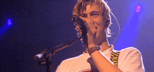a man is singing into a microphone on a stage in front of a crowd .