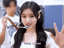 a girl with a microphone in her mouth is wearing a maison shirt