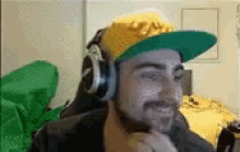 a man wearing headphones and a green hat is sitting in a chair .