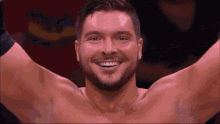 a shirtless wrestler is smiling with his arms outstretched