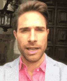 a man wearing a pink shirt and a gray jacket