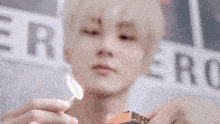 a close up of a person holding a lit match in front of a sign that says ero