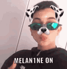 a young man wearing a dalmatian mask and sunglasses is making a funny face .