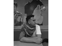 a black and white photo of a man sitting at a table in front of a sign that says coca cola