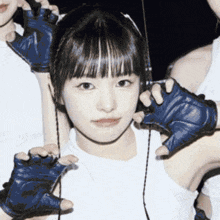a girl wearing headphones and blue gloves looks at the camera