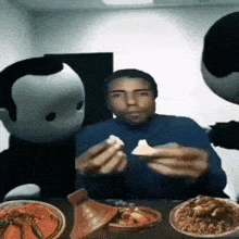 a man is sitting at a table with plates of food and two cartoon characters behind him