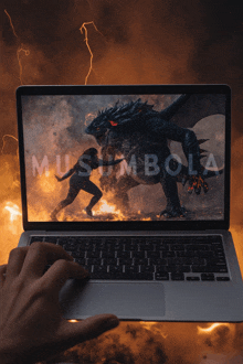 a person is typing on a laptop with a picture of a dragon on the screen and the word musamba on it