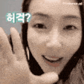 a close up of a woman 's face with a hand waving in front of her .