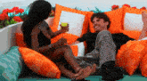a man and woman are sitting on a couch with orange pillows