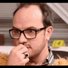 a man wearing glasses and a ring on his finger