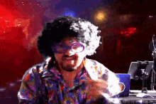 a man with an afro and glasses is sitting in front of a computer