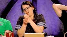a woman wearing glasses sits at a table with her hands folded in front of a tablet ..