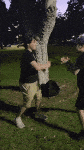 two men are standing next to each other in a park with a tree in the background