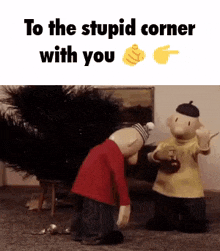 two stuffed animals are kneeling next to a christmas tree and a sign that says `` to the stupid corner with you '' .