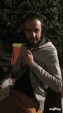 a man is wearing a grey hoodie and a black shirt