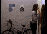 a woman standing next to a bicycle in front of a picture on the wall