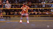 a wrestler in a wrestling ring with a referee standing behind him