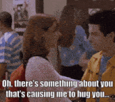 a man in a yellow jacket is hugging a woman in a white sweater in a hallway