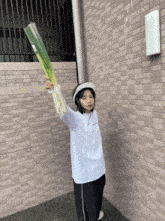 a girl wearing a white shirt with the word champion on it is holding a large green vegetable