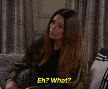 a woman sitting on a couch with the words eh ? what behind her