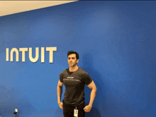 a man stands in front of a blue wall that has the word intuitit on it