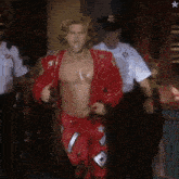 a man in a red jacket and red pants is being escorted by two men