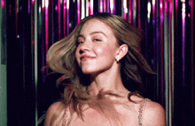 a woman in a dress is dancing in front of a pink curtain .
