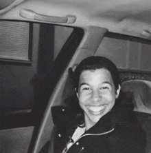 a black and white photo of a woman in a car smiling