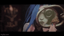 a woman with blue hair is holding a mirror and looking at herself in it .