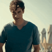 a young man in a blue shirt is smiling and looking at the camera
