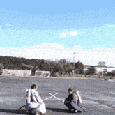 two people holding swords in a parking lot with a blue sky in the background