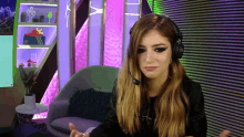 a woman wearing headphones with a microphone on her head looks at the camera