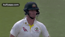 a cricket player wearing a helmet and a white shirt with a qantas logo on it .