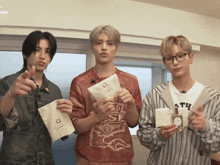 three young men are holding a bottle of perfume and a bag that says a on it