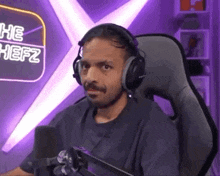 a man wearing headphones is sitting in front of a microphone in a chair .