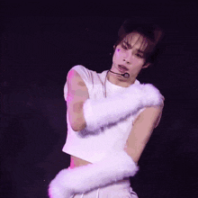 a man wearing a white crop top and white furry gloves