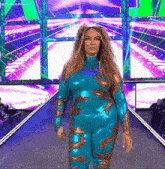 a woman in a blue and gold bodysuit is walking down a stage .