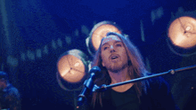 a man singing into a microphone with the words " you must think i 'm a masochi " in the background